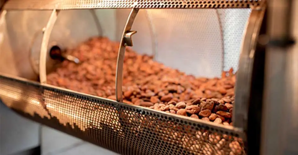 Brown cocoa beans in a cylindrical roaster.