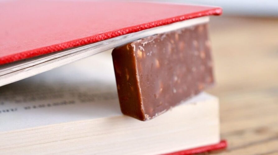 A piece of chocolate between book pages.